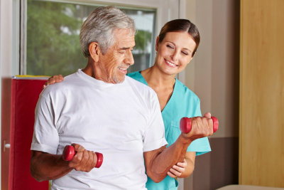 Senior man with dumbbells in rehab with a physiotherapist